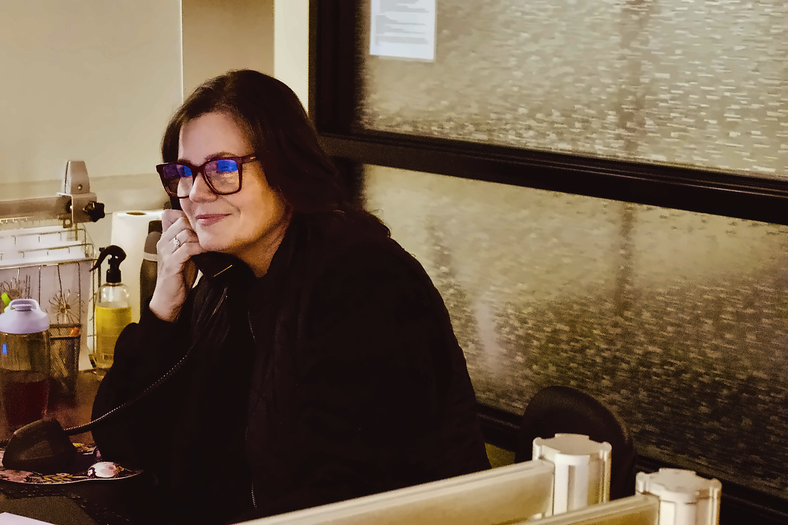 A smiling woman talking on the phone at the Cooper Chiropractic front desk.